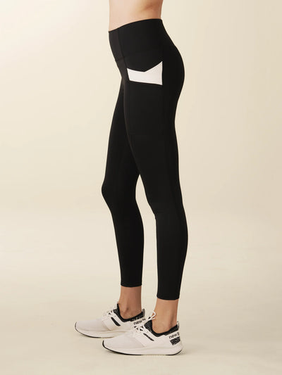 Model wears full length crossover deep pocket leggings in black and cream