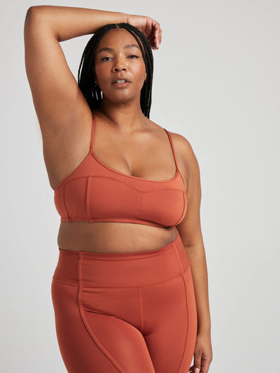 Model poses in burnt orange bralette with corset boning