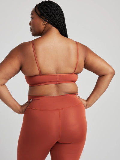 Model poses in burnt orange bralette with corset boning