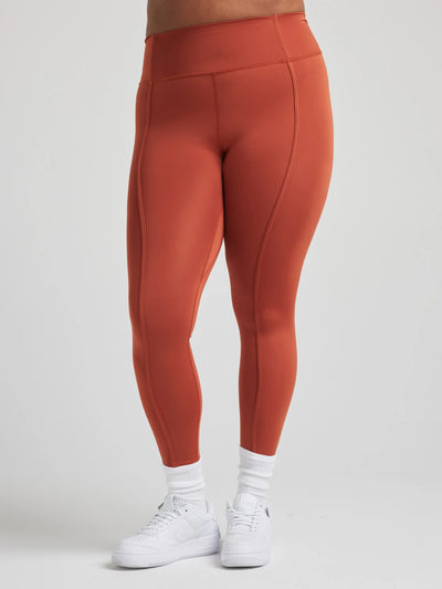 model poses in burnt orange leggings with corset boning