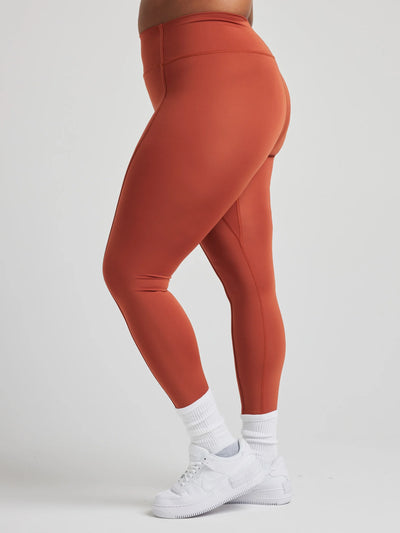 model poses in burnt orange leggings with corset boning