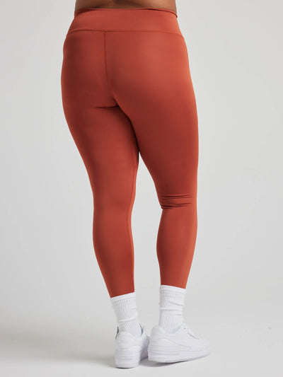 model poses in burnt orange leggings with corset boning