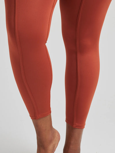 model poses in burnt orange leggings with corset boning