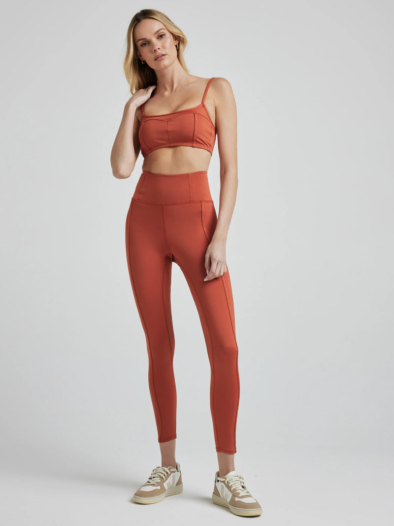 model poses in burnt orange leggings with corset boning