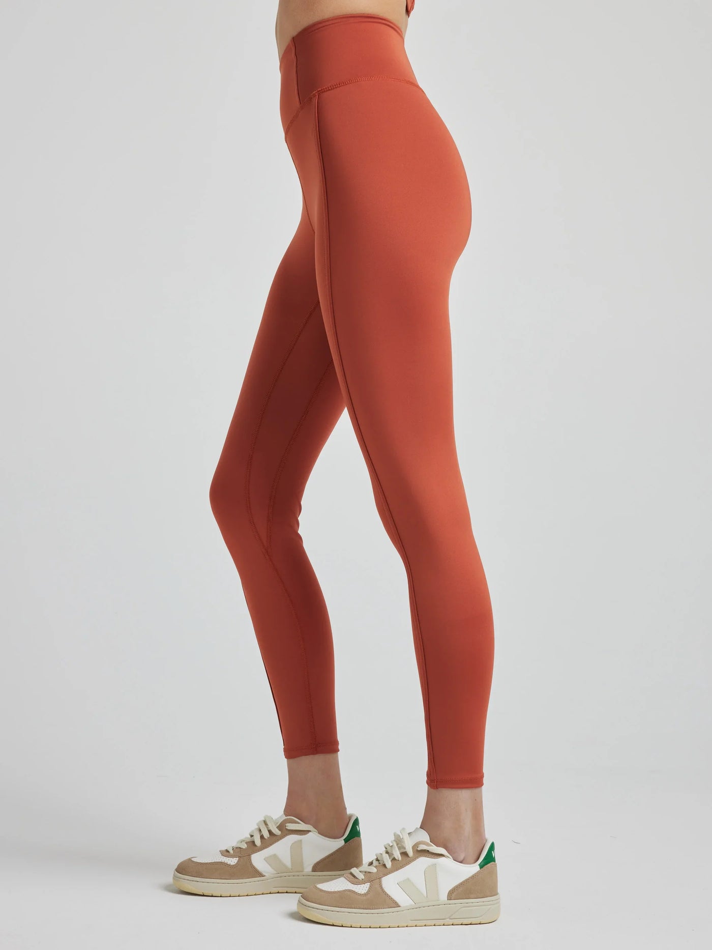 model poses in burnt orange leggings with corset boning