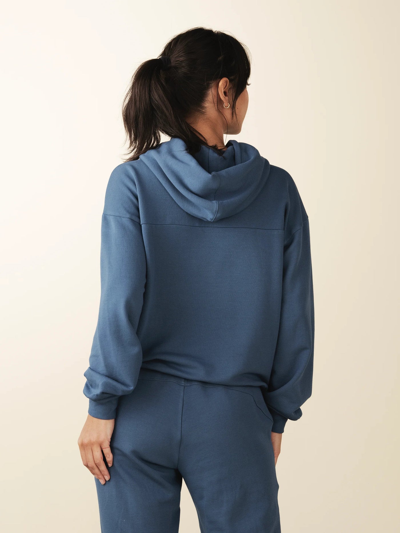 model wears cozy sustainable hoodie with pocket in blue